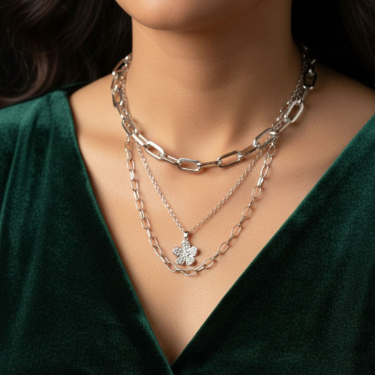 Layered silver necklaces on a mannequin with a green top