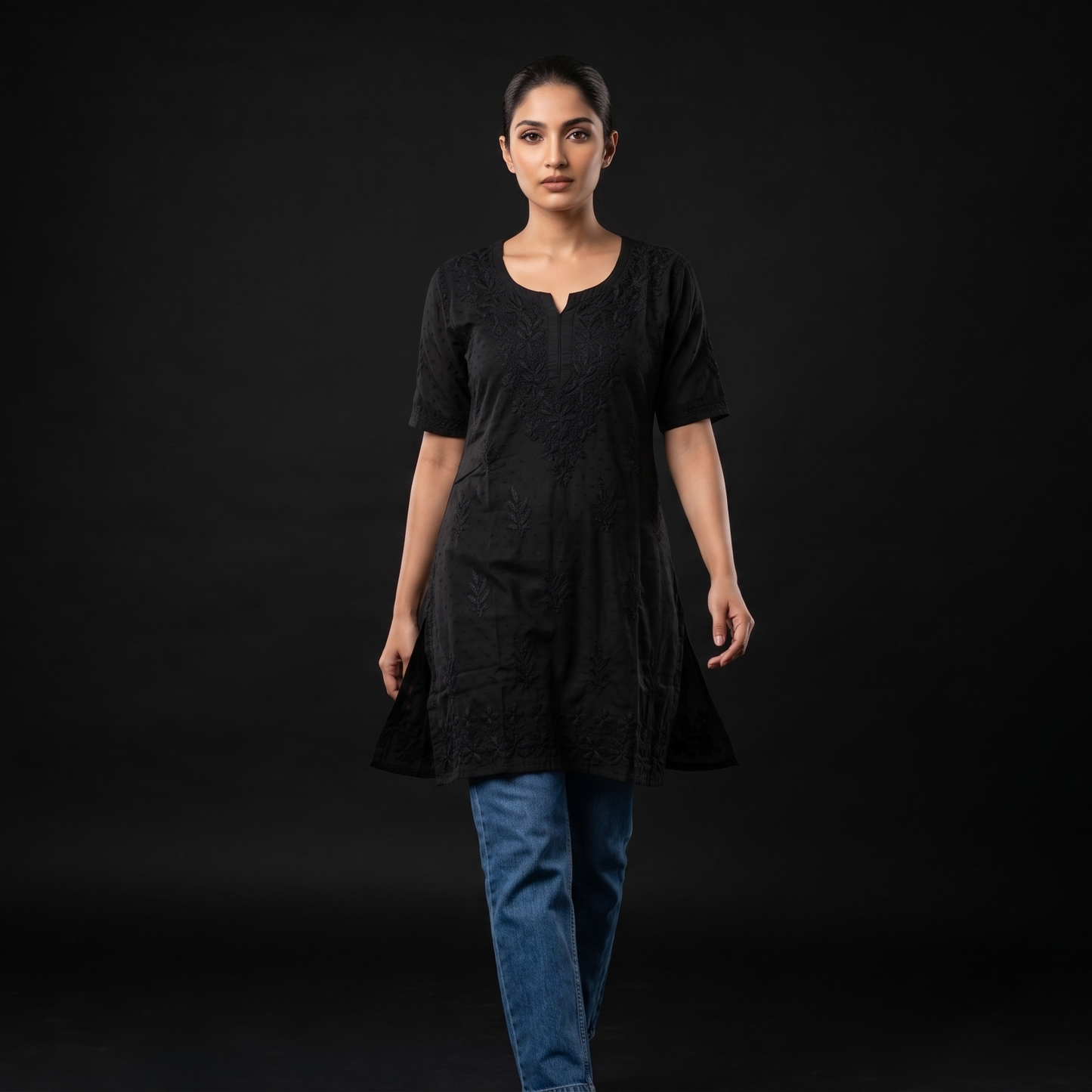 Woman wearing a black dress and blue jeans on a black background