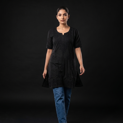 Woman wearing a black dress and blue jeans on a black background